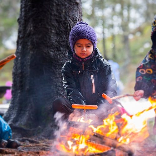Grille pølser på bål er alltid populært. Yasmin (9) koser seg ved bålet. (Foto: André Marton Pedersen)