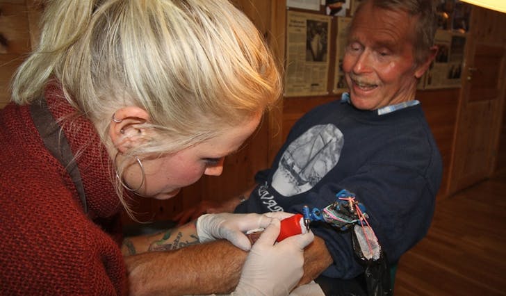 Karoline Hille Nordstrønen tatoverer ein oselvar på John Lepsøy sin høgrearm. (Foto: Kjetil Vasby Bruarøy)
