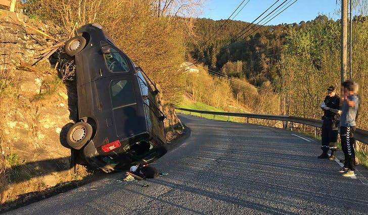 Bilen trilla frå ein eigedom over Søvikvegen og utfor ein fjellskrent før den landa loddrett i Søvikvegen. (Foto: Kjetil Vasby Bruarøy)