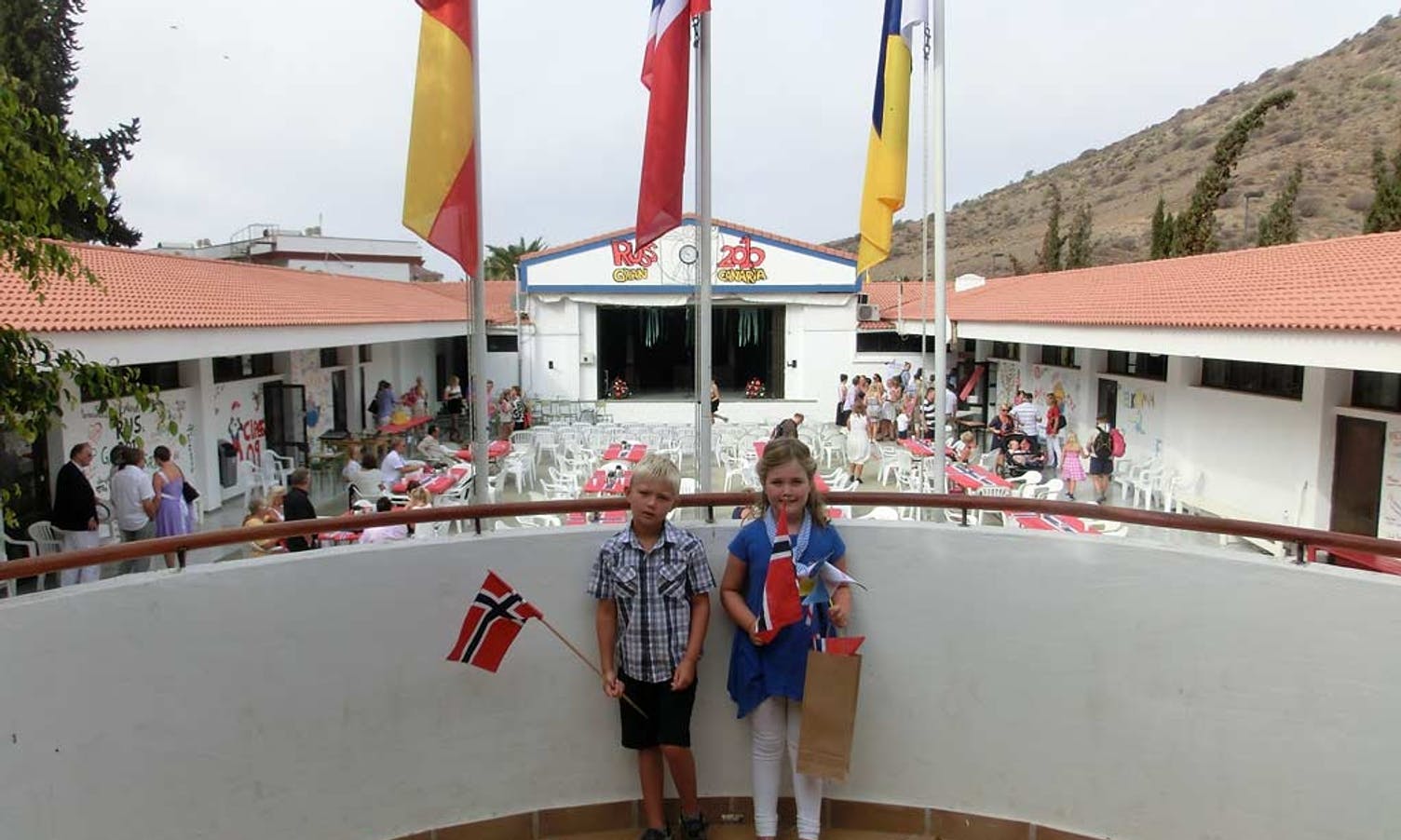 Flagga, det spanske, norske og canariske er heist til topps i skulegarden/patioen på Colegio Noruega. Petter Dale (6) og Sofia (7) (privat foto)
